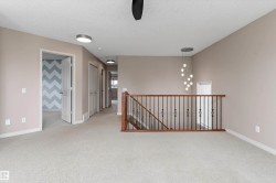 Carpeted flooring throughout, with a wood and wrought iron staircase railing, and a contemporary chandelier - 