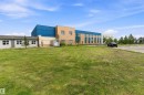 Exterior building featuring a combination of brick, metal siding, and stucco finishes, multiple window installations, and a surrounding green space - 20845 92A Avenue Nw, Edmonton, AB  - Outdoor 