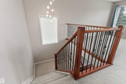 Staircase with wood-finish handrails, decorative wrought iron balusters, and carpeted treads - 