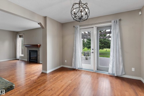 Wood-finish flooring throughout, wrought iron chandelier, glass panel patio doors, and a fireplace with a wood mantle - 20845 92A Avenue Nw, Edmonton, AB - Indoor With Fireplace