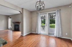 Wood-finish flooring throughout, wrought iron chandelier, glass panel patio doors, and a fireplace with a wood mantle - 