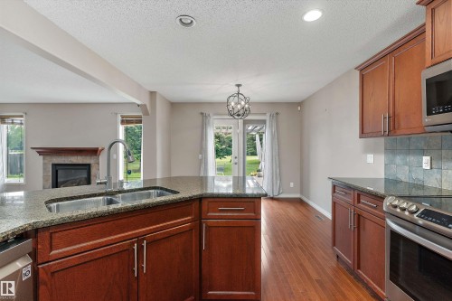 Kitchen with wood-finish cabinetry, granite countertops, and stainless steel appliances - 20845 92A Avenue Nw, Edmonton, AB - Indoor Photo Showing Kitchen With Double Sink