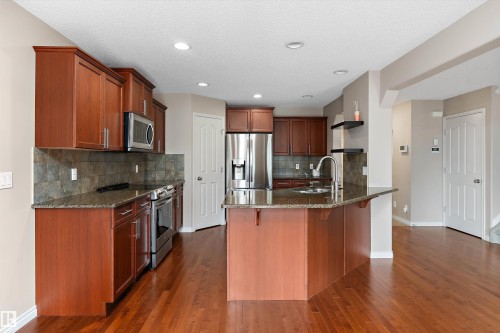 Kitchen featuring wood-finish flooring, dark wood cabinetry, a central island with a sink, stainless steel appliances, and recessed lighting - 20845 92A Avenue Nw, Edmonton, AB - Indoor Photo Showing Kitchen