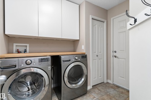 Laundry area featuring white cabinetry, a wood-finish countertop, and tile flooring - 20845 92A Avenue Nw, Edmonton, AB - Indoor Photo Showing Laundry Room