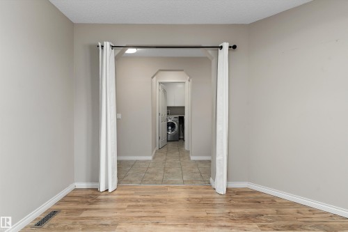 Wood-finish flooring, light neutral wall paint, and a tiled utility area with overhead cabinetry - 20845 92A Avenue Nw, Edmonton, AB - Indoor Photo Showing Other Room