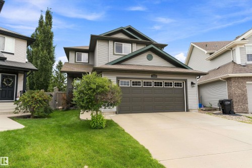 Two-story residence featuring light gray siding, dark green trim, an attached garage with a dark panel door, and a concrete driveway - 20845 92A Avenue Nw, Edmonton, AB - Outdoor
