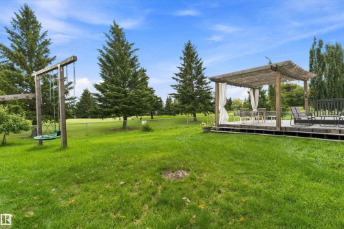 Expansive lawn with mature trees, a multi-level deck, a pergola with draped curtains, and a swing set - 20845 92A Avenue Nw, Edmonton, AB - Outdoor