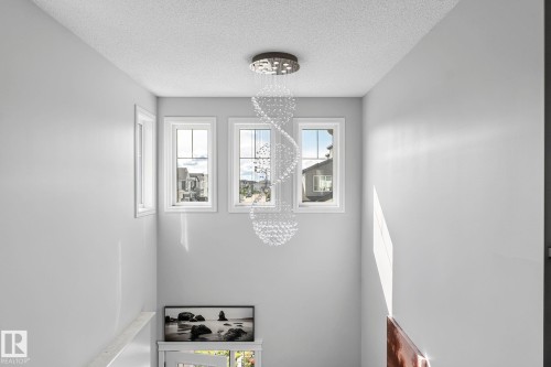 Spiral crystal chandelier illumination, light gray wall paint, three transom windows, white window trim - 923 174St Sw, Edmonton, AB 