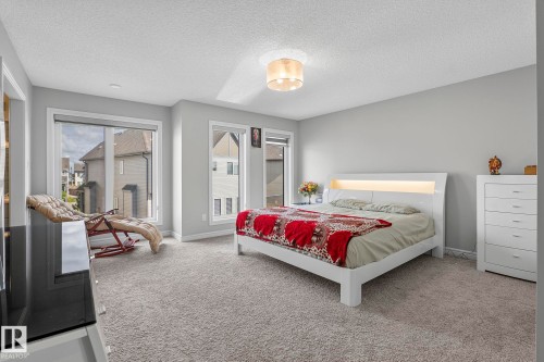 Wall-to-wall carpeting, multiple windows with white trim, light gray painted walls, and a ceiling-mounted light fixture - 923 174St Sw, Edmonton, AB 