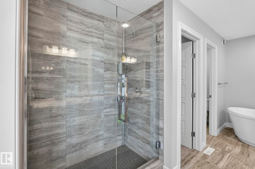 Glass-enclosed shower with large format tile walls and a hexagonal tile floor - 923 174St Sw, Edmonton, AB 