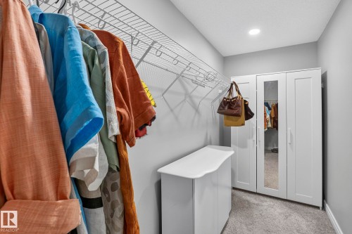 Carpeted closet space featuring a built-in wire shelving system, recessed ceiling lighting, and a freestanding white storage unit - 923 174St Sw, Edmonton, AB 