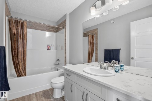 White vanity with chrome hardware, an integrated sink, and a stone-finish countertop - 923 174St Sw, Edmonton, AB 