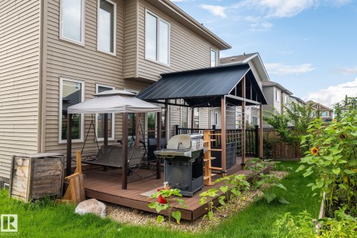 Expansive backyard featuring a manicured lawn, a raised garden bed, and a full-sized deck with a covered gazebo - 923 174St Sw, Edmonton, AB 