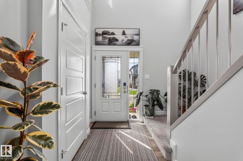 Entryway featuring a paneled door, decorative glass front door, and a staircase with a wood handrail and metal balusters - 923 174St Sw, Edmonton, AB 
