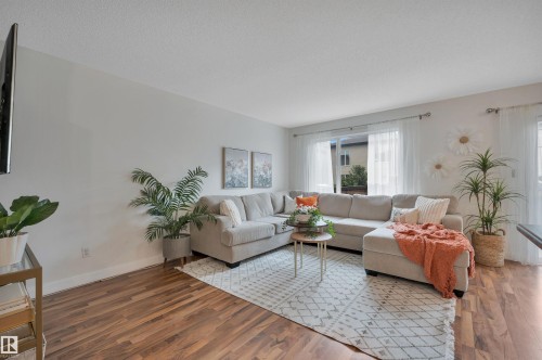 Expansive living area with wood-finish flooring, white walls, and a large sliding glass door - 17321 8A Avenue Sw, Edmonton, AB - Indoor Photo Showing Living Room