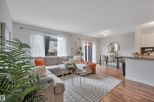 Open-concept living space featuring wood-finish flooring, a sliding glass door, and recessed lighting - 17321 8A Avenue Sw, Edmonton, AB - Indoor Photo Showing Living Room