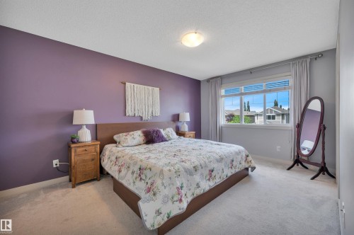 Carpeted flooring, wood-finish headboard, flush-mount ceiling light, window with horizontal blinds and drapes, and a wood-finish nightstand - 17321 8A Avenue Sw, Edmonton, AB - Indoor Photo Showing Bedroom