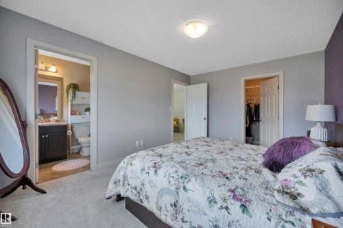 Neutral wall palette, ceiling-mounted light fixture, light carpeting, en-suite bathroom access, and a walk-in closet - 17321 8A Avenue Sw, Edmonton, AB - Indoor Photo Showing Bedroom
