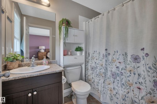 Vanity with integrated sink, dark wood-finish cabinetry, and a speckled countertop - 17321 8A Avenue Sw, Edmonton, AB - Indoor Photo Showing Bathroom