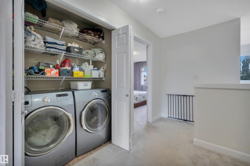 Built-in closet with wire shelving and front-load washer and dryer - 17321 8A Avenue Sw, Edmonton, AB - Indoor Photo Showing Laundry Room