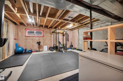 Unfinished basement with exposed ceiling joists and concrete walls, featuring a window, ductwork, and built-in shelving - 17321 8A Avenue Sw, Edmonton, AB - Indoor Photo Showing Basement