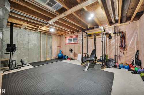 Unfinished basement with exposed ceiling joists and concrete walls, featuring a small horizontal window - 17321 8A Avenue Sw, Edmonton, AB - Indoor Photo Showing Basement