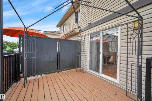 Outdoor deck featuring composite wood flooring, black metal railing, and a sliding glass door - 17321 8A Avenue Sw, Edmonton, AB - Outdoor With Deck Patio Veranda With Exterior