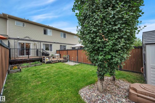Expansive backyard with a wooden fence, large deck, sliding glass door, and a built-in outdoor storage shed - 17321 8A Avenue Sw, Edmonton, AB - Outdoor With Deck Patio Veranda With Exterior