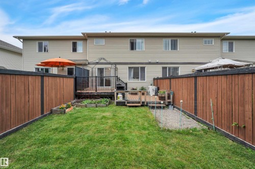 Manicured lawn with wood fencing and a multi-level deck featuring a black metal railing and exterior siding - 17321 8A Avenue Sw, Edmonton, AB - Outdoor With Deck Patio Veranda With Exterior