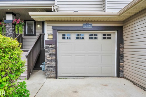 Beige garage door with window inserts, stone pillar accents, and light-toned siding - 17321 8A Avenue Sw, Edmonton, AB - Outdoor