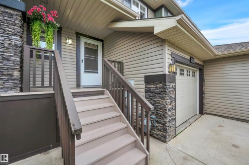 Exterior featuring stacked stone pillars, horizontal siding, and a paneled garage door - 17321 8A Avenue Sw, Edmonton, AB - Outdoor