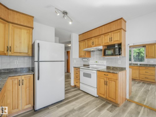 Kitchen featuring wood-finish cabinetry, stone-finish countertops, tile backsplash, and wood-finish flooring - 16428 88 Avenue Nw, Edmonton, AB - Indoor Photo Showing Kitchen