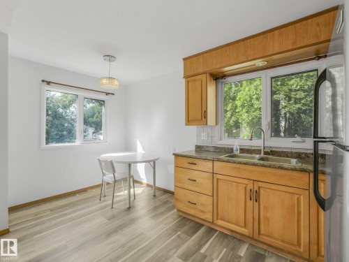 Kitchen featuring light wood cabinetry, stone-finish countertops, stainless steel dual-basin sink, and a tiled backsplash - 16428 88 Avenue Nw, Edmonton, AB - Indoor Photo Showing Kitchen With Double Sink