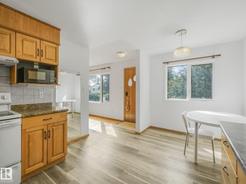 Kitchen featuring wood cabinetry, a tiled backsplash, and stone-look countertops - 16428 88 Avenue Nw, Edmonton, AB - Indoor Photo Showing Kitchen