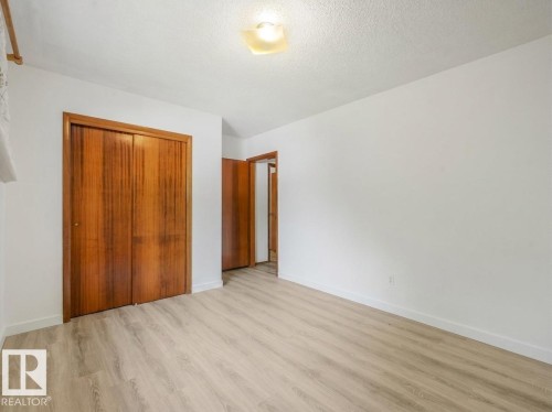 Light wood-finish flooring with white walls - 16428 88 Avenue Nw, Edmonton, AB - Indoor Photo Showing Other Room