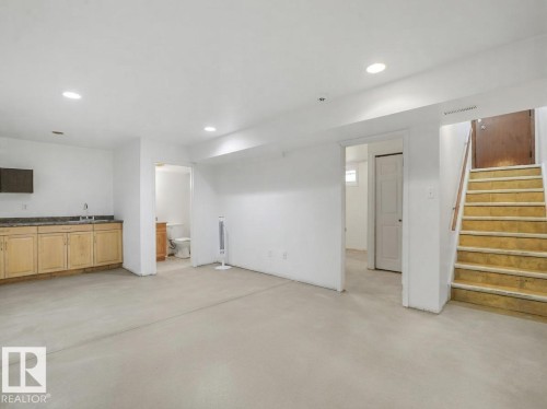Recessed lighting, light-toned flooring, built-in cabinetry with sink, and a staircase with a wooden handrail - 16428 88 Avenue Nw, Edmonton, AB - Indoor