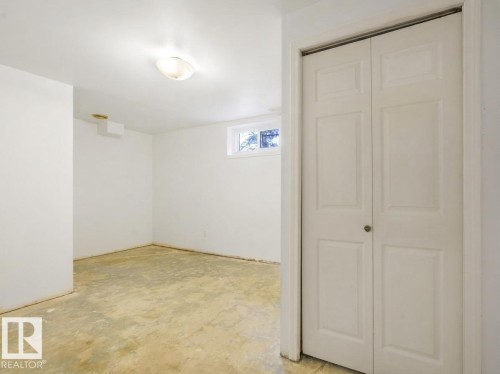 Recessed window, ceiling-mounted light fixture, white bi-fold closet doors, painted walls, and concrete flooring - 16428 88 Avenue Nw, Edmonton, AB - Indoor Photo Showing Other Room