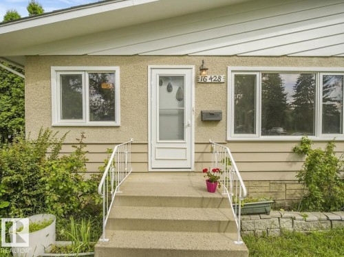 Stucco exterior with horizontal siding accents, white framed windows, and a concrete entry staircase with metal railings - 16428 88 Avenue Nw, Edmonton, AB - Outdoor