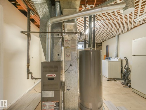 Utility area featuring a Lennox furnace, water heater, and exposed ceiling joists with lattice-style covering - 16428 88 Avenue Nw, Edmonton, AB - Indoor Photo Showing Basement
