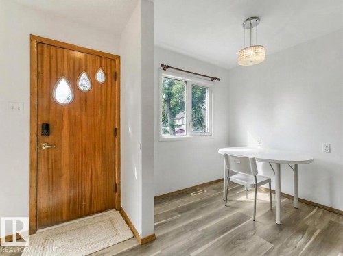 Wood-finish flooring, white walls, and a contemporary pendant light fixture - 16428 88 Avenue Nw, Edmonton, AB - Indoor Photo Showing Other Room