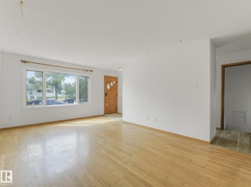 Hardwood flooring, natural light through large windows, white walls, and a wood-finish entry door - 16428 88 Avenue Nw, Edmonton, AB - Indoor