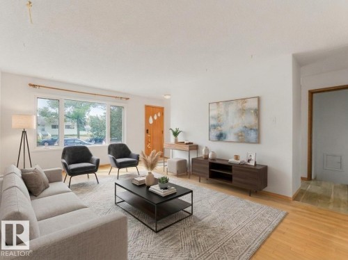 Bright living area featuring wood-finish flooring, a large multi-pane window, and a light-toned area rug - 16428 88 Avenue Nw, Edmonton, AB - Indoor Photo Showing Living Room