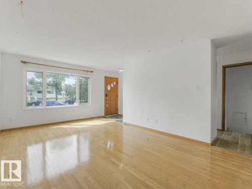 Hardwood flooring, front entry door, large picture window, white painted walls, and built-in ceiling lighting - 16428 88 Avenue Nw, Edmonton, AB - Indoor Photo Showing Other Room