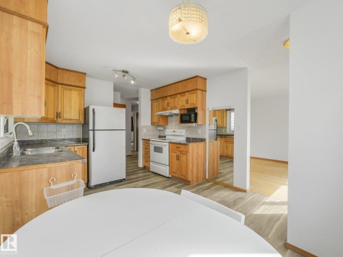 Kitchen featuring wood cabinetry, stainless steel sink, and light-toned flooring - 16428 88 Avenue Nw, Edmonton, AB - Indoor Photo Showing Kitchen