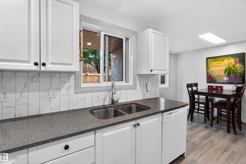 Kitchen featuring white shaker-style cabinetry, a dual basin stainless steel sink, and a dishwasher - #28 3645 145 Av Nw, Edmonton, AB - Indoor Photo Showing Kitchen With Double Sink