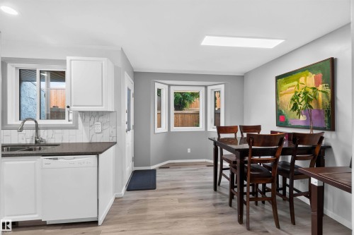 Kitchen area with white cabinetry, dark countertops, and a white subway tile backsplash - #28 3645 145 Av Nw, Edmonton, AB - Indoor