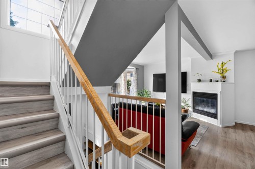 Wood-finish stairs with white balusters, natural wood handrail, and upper window - #28 3645 145 Av Nw, Edmonton, AB - Indoor Photo Showing Other Room