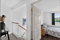 Hardwood flooring, window with exterior scenery, white wall finishes, paneled door, and carpeted stairs with a wood and metal railing - 