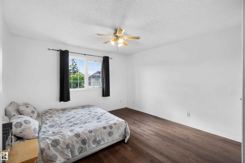 Dark wood-finish flooring with white walls and a white textured ceiling - #28 3645 145 Av Nw, Edmonton, AB - Indoor Photo Showing Bedroom