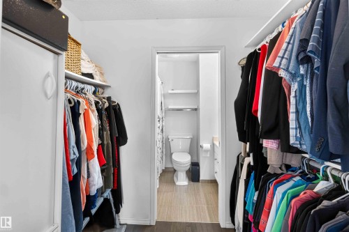 Walk-in closet featuring built-in shelving, hanging rods, and a sliding closet door - #28 3645 145 Av Nw, Edmonton, AB - Indoor With Storage